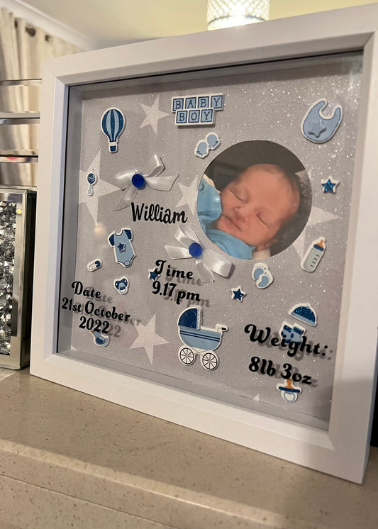 Framed baby milestone display with photo and text on a gray background