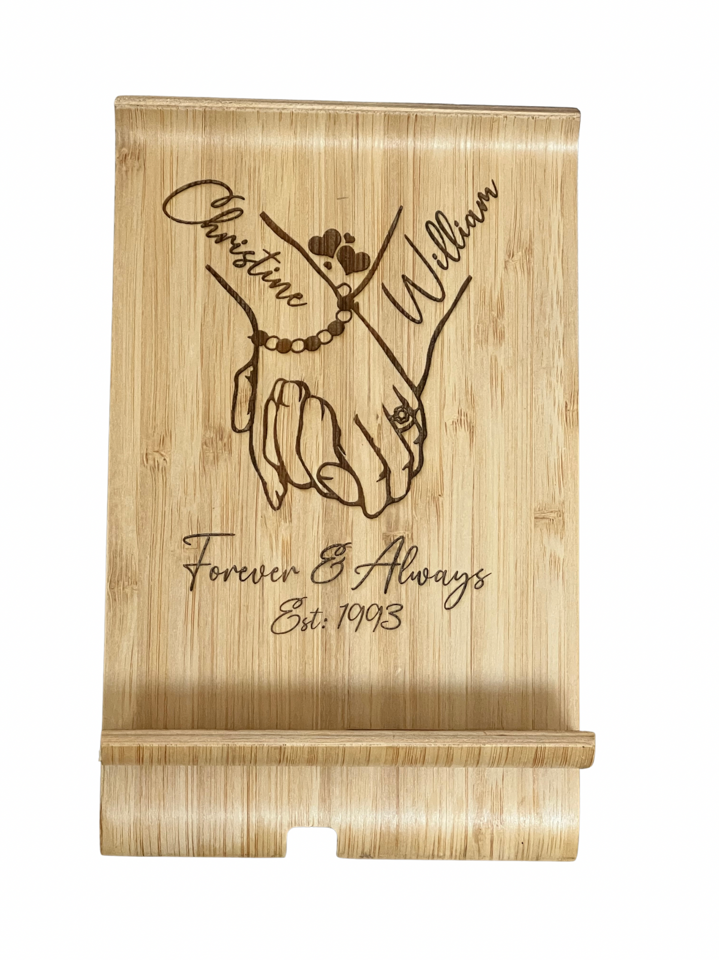 A unique personalised bamboo phone stand laser-engraved with a couple holding hands, two names & a date. Perfect wedding, anniversary or Valentine's gift.