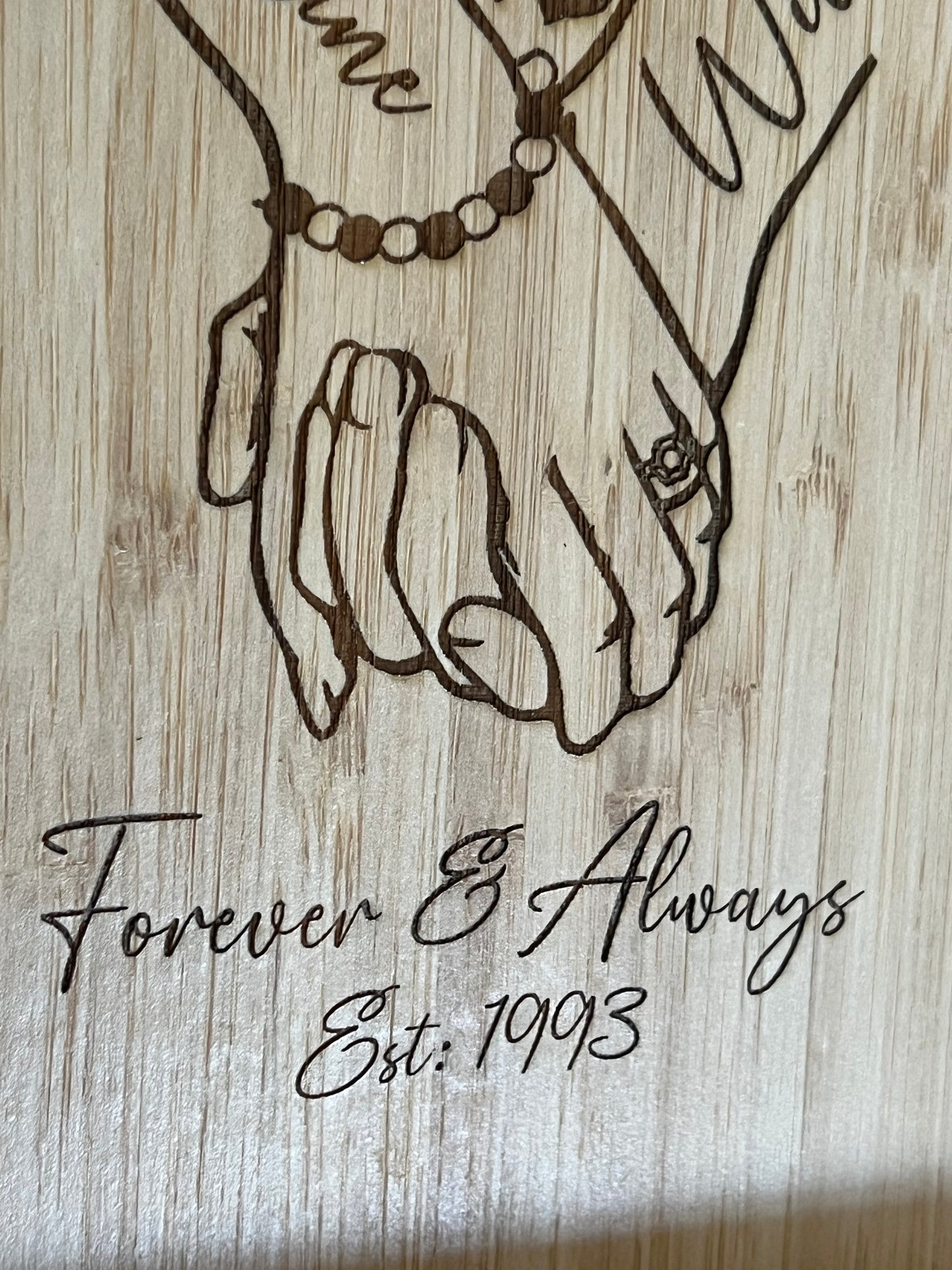 A unique personalised bamboo phone stand laser-engraved with a couple holding hands, two names & a date. Perfect wedding, anniversary or Valentine's gift.
